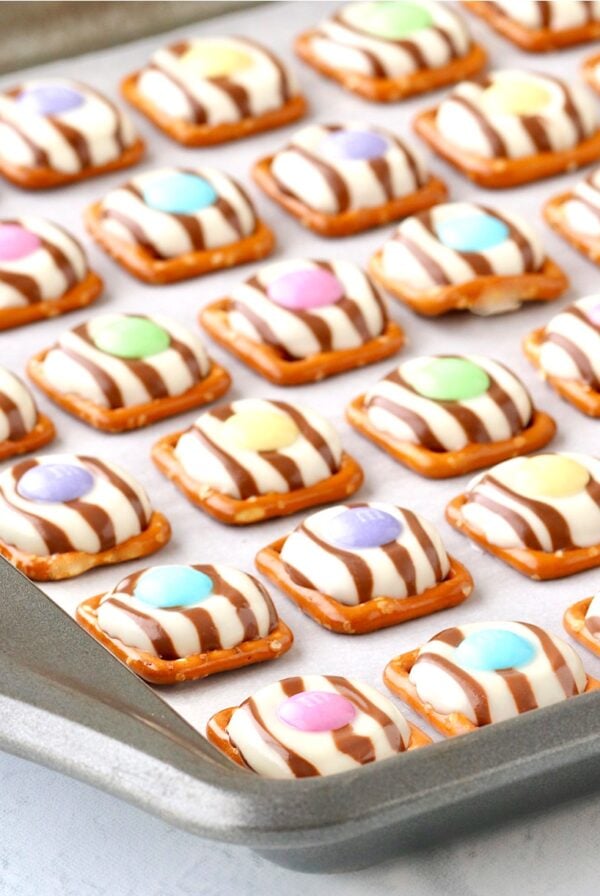 Easter pretzel treats with Hershey Hugs and spring M&M's on cookie sheet.