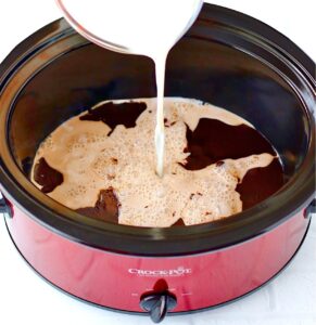 Milk being poured into slow cooker to make crockpot hot chocolate.