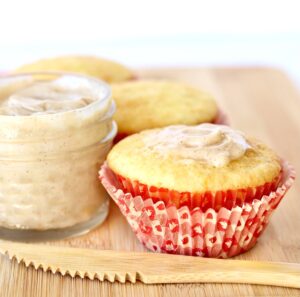 Three cornbread muffins on cutting board with butter and knife to the side.