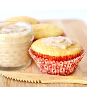 Three cornbread muffins on cutting board with butter and knife to the side.