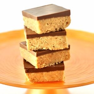 Stack of four chocolate peanut butter bars on orange cake stand.
