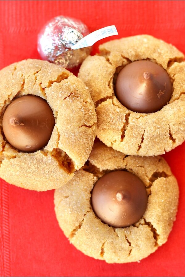 Three peanut butter kiss cookies on napkin.