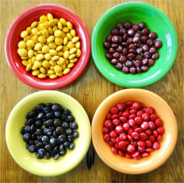 Four small bowls filled with peanut butter M&M's.
