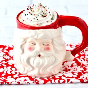 Peppermint mocha in Santa mug with whip cream and sprinkles on top.