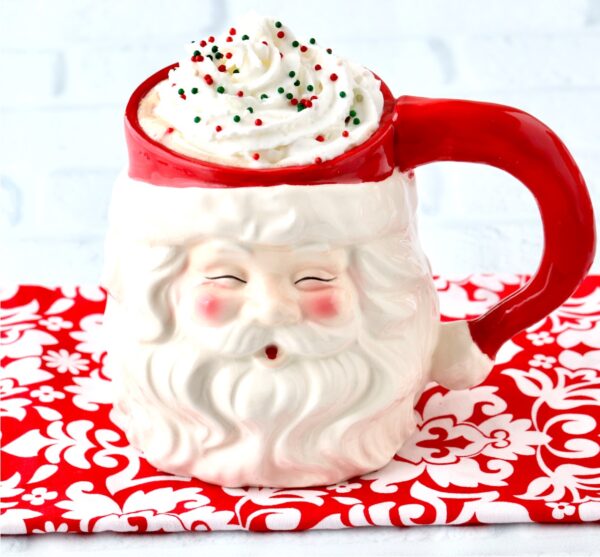 Peppermint mocha in Santa mug with whip cream and sprinkles on top.