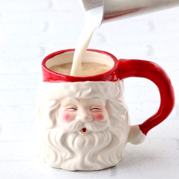 Milk being poured into a Santa mug to make a peppermint mocha.