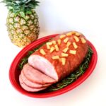 Ham on platter with brown sugar pineapple glaze, and pineapple tidbits on top.
