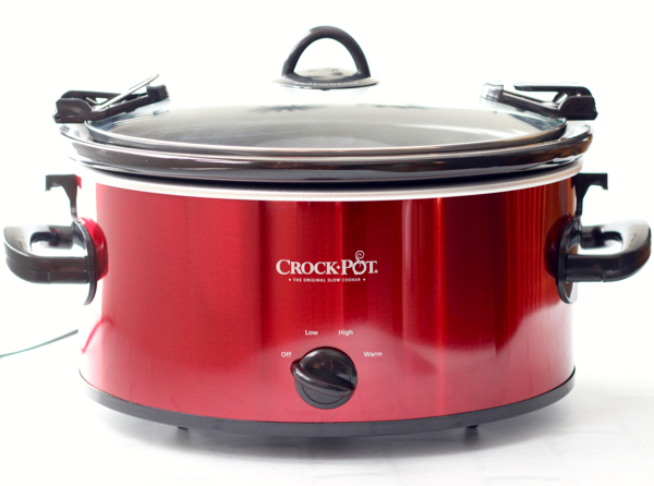 Red crockpot cooking pineapple juice glazed ham.