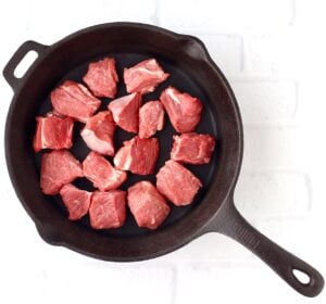Beef in cast iron skillet cooking.