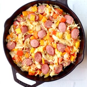 Kielbasa sausage and bell peppers with onion and sauerkraut in skillet.