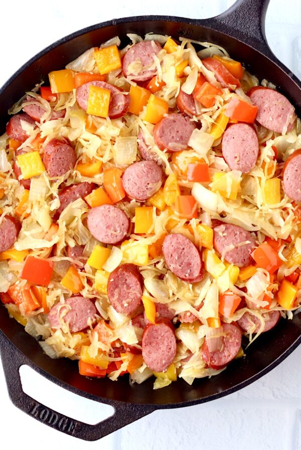 Kielbasa sausage and bell peppers with onion and sauerkraut in skillet.