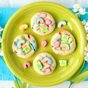 Four St. Patrick's Day cookies with Lucky Charms marshmallows on plate.