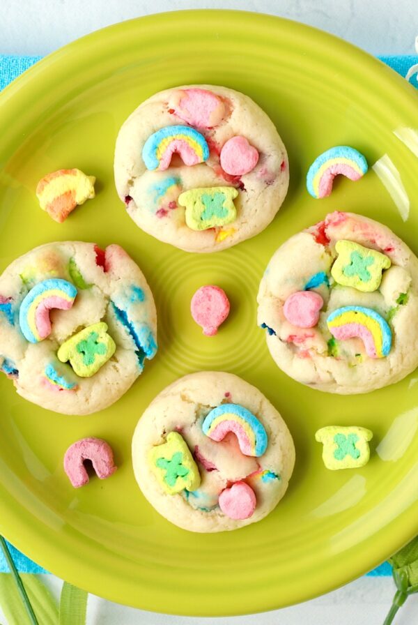 Four St. Patrick's Day cookies with Lucky Charms marshmallows on plate.