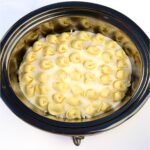 Cheese tortellini with alfredo sauce and mozzarella cheese in crockpot.