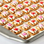 Valentine pretzel treats with Hershey Hugs and spring M&M's on cookie sheet.