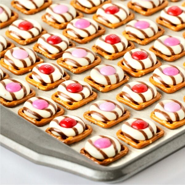 Valentine pretzel treats with Hershey Hugs and spring M&M's on cookie sheet.