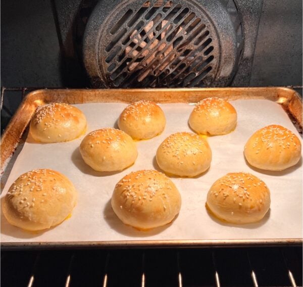 Slider buns baking on cookie sheet in oven.