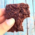 Hand holding black bean brownie with bite taken out of it.