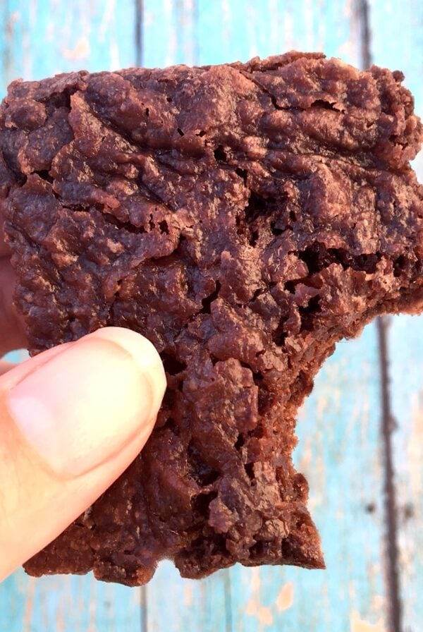 Hand holding black bean brownie with bite taken out of it.