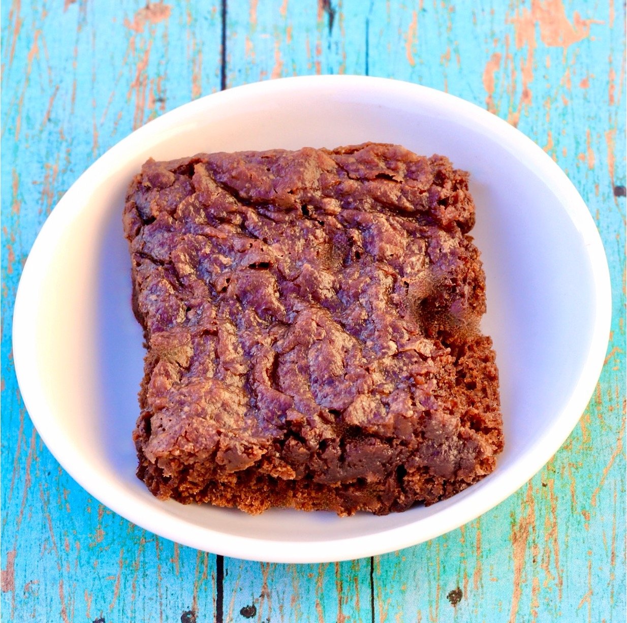 Black bean brownie cut into a square on small white dish.