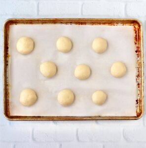 Dough balls for burger slider buns on cookie sheet.
