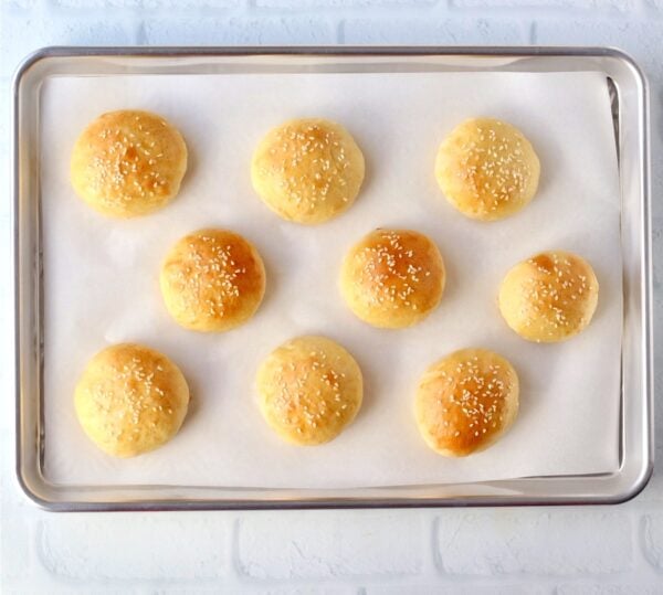 Baked mini slider buns for burgers on cookie sheet.