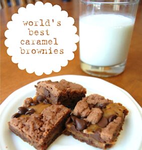 Three chocolate caramel brownies on plate with glass of milk in background.