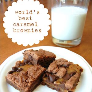 Three chocolate caramel brownies on plate with glass of milk in background.