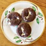 Three double chocolate chip cupcakes with cream cheese on plate.