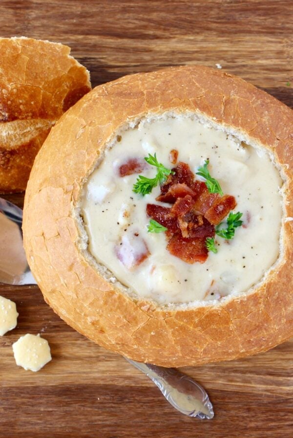 Clam chowder in bread bowl, garnished with bacon and parsley.