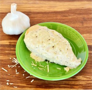 Garlic Parmesan Chicken on plate with fresh garlic in background.