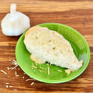 Garlic Parmesan Chicken on plate with fresh garlic in background.