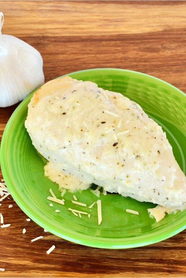 Garlic Parmesan Chicken on plate with fresh garlic in background.