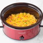 Crockpot chicken and rice casserole in crockpot, topped with bacon and green onions.