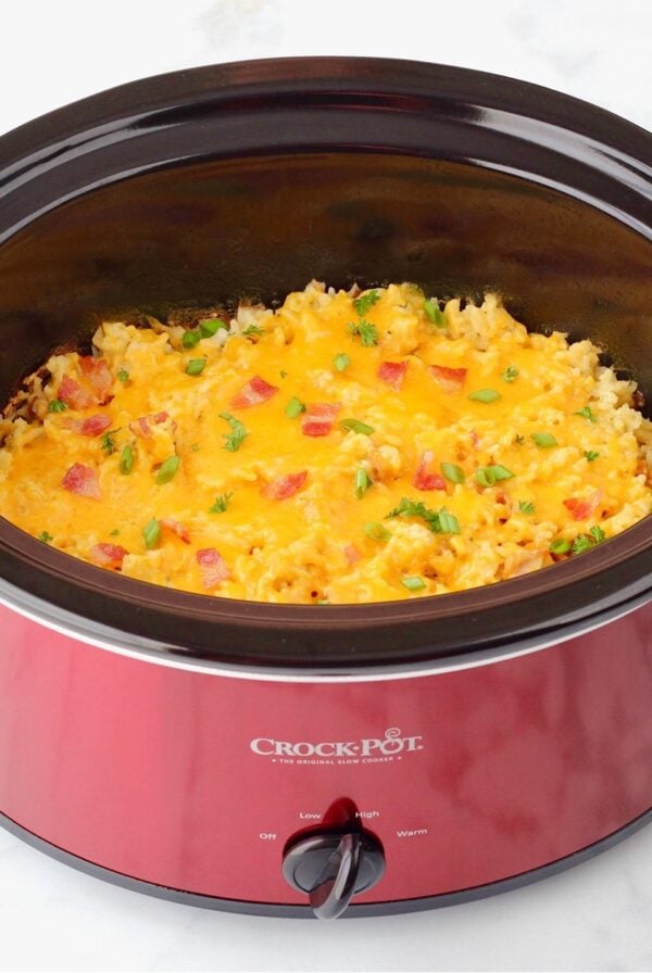 Crockpot chicken and rice casserole in crockpot, topped with bacon and green onions.