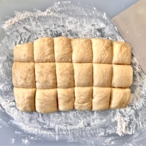 Slider bun dough with bench scraper to the side.