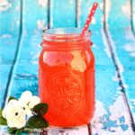 Red fruit punch in mason jar with straw.