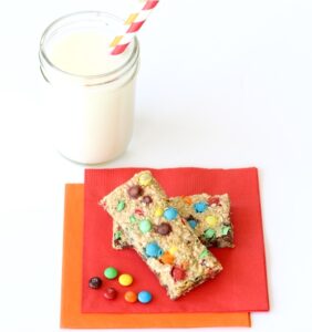 Granola bars on napkins with a glass of milk.
