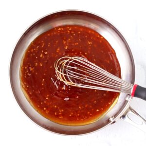 Homemade teriyaki sauce in sauce pan with whisk.