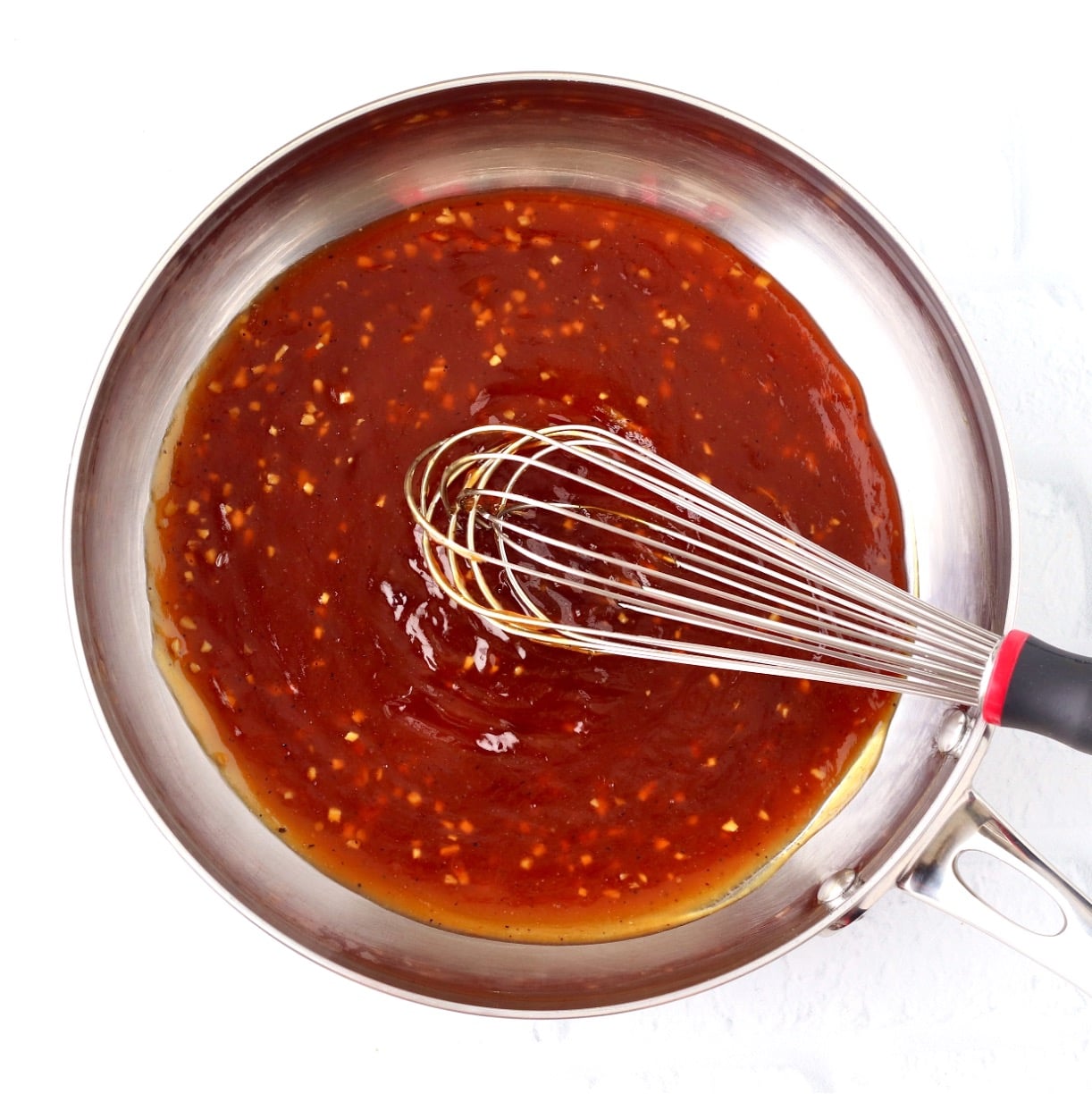 Homemade teriyaki sauce in sauce pan with whisk.