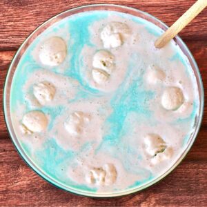 Blue party punch with scoops of vanilla ice cream floating in punch bowl.