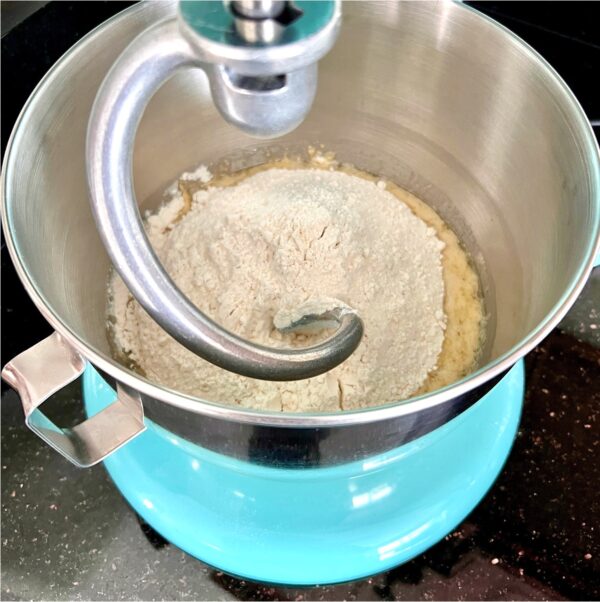 Kitchenaid Stand Mixer with dough hook attachment and flour in mixing bowl.