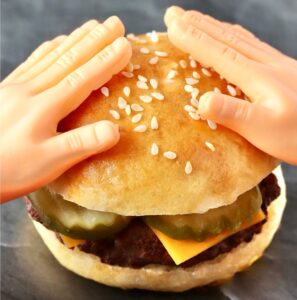 Tiny hands on top of mini burger slider bun.