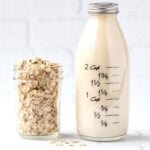 Oat milk in glass bottle with jar of oats to the side.