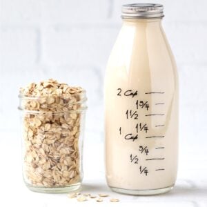 Oat milk in glass bottle with jar of oats to the side.
