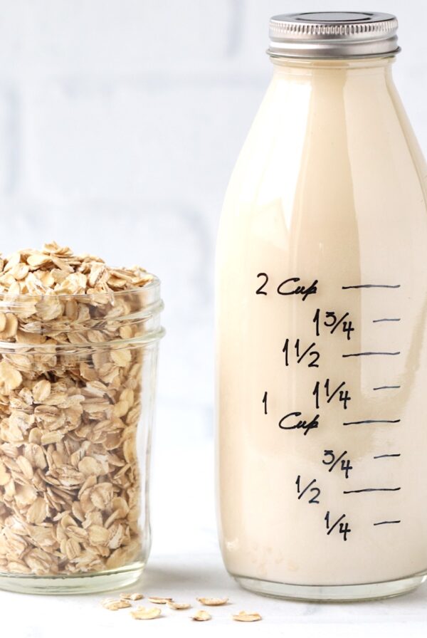 Oat milk in glass bottle with jar of oats to the side.
