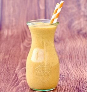 Pumpkin spice milkshake in jar with two orange striped straws.