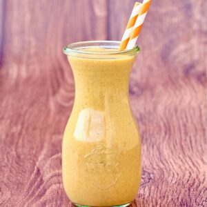 Pumpkin spice milkshake in jar with two orange striped straws.