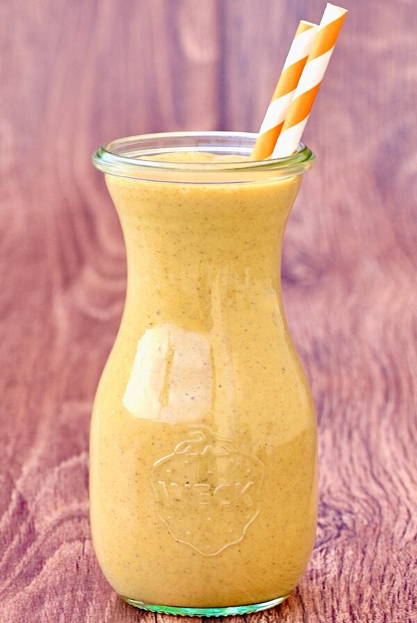 Pumpkin spice milkshake in jar with two orange striped straws.