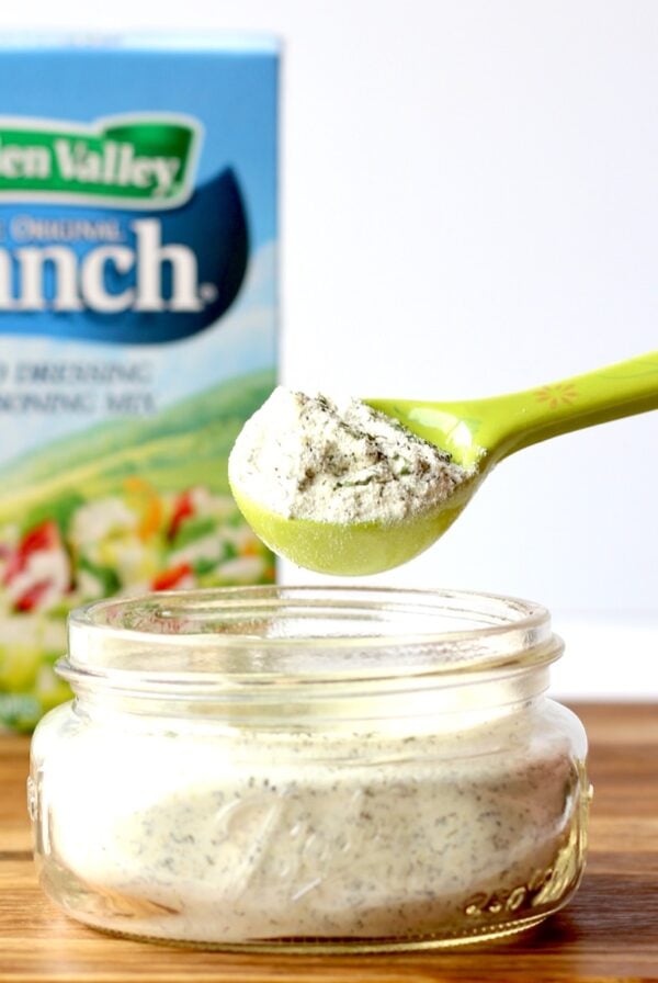 Homemade ranch dressing mix on tablespoon, with Hidden Valley Ranch packet in background.